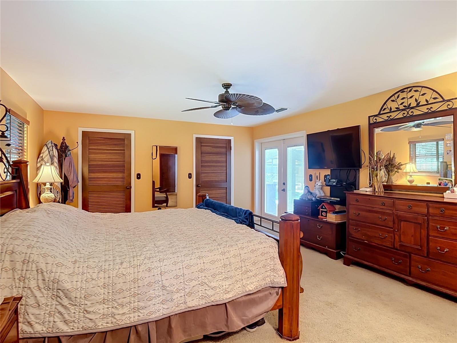 spacious primary bedroom with french doors to covered lanai and screened pool, two walk in closets - 2269 COUNTRY CLUB DR, DELAND