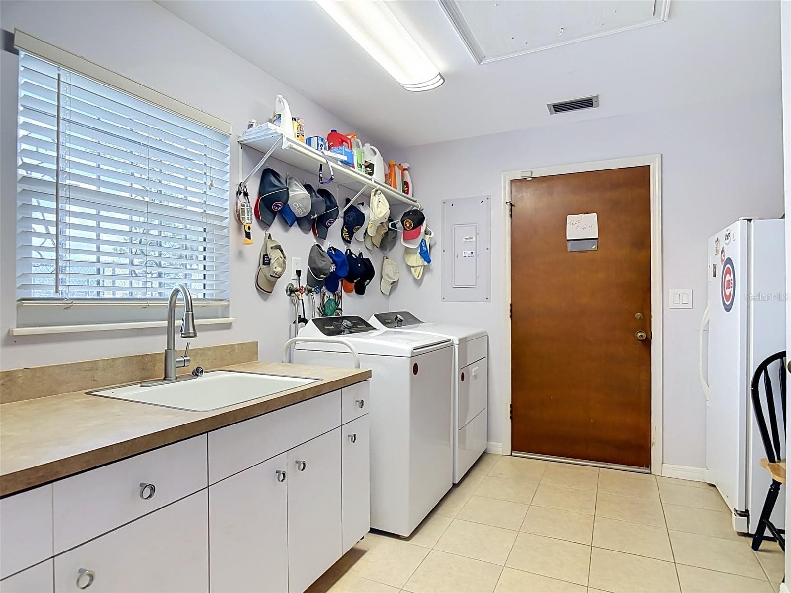 utility room with wash sink, counter space for folding clothes, door to garage, and stand up freezer. - 2269 COUNTRY CLUB DR, DELAND