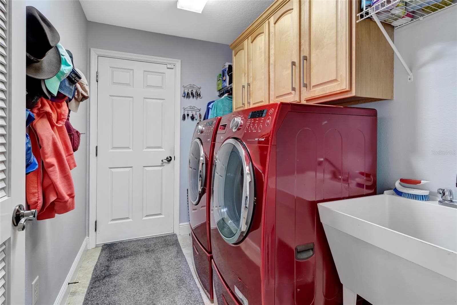 Inside laundry room with updated washer and dryer. Utility sink and wood cabinets located just off the garage. - 4190 COUNTY ROAD 121D, WILDWOOD