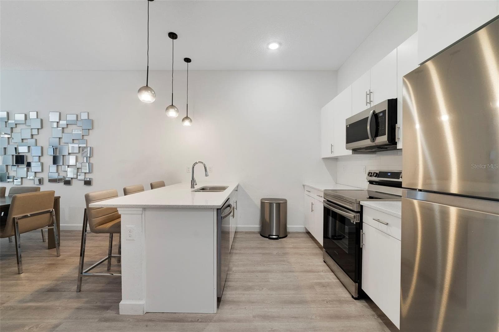 The open kitchen features STAINLESS STEEL APPLIANCES, sleek countertops, complementary cabinetry, tiled backsplash and a breakfast bar with pendant lighting perfect for casual dining or entertaining. - 340 FAMAGUSTA DR, DAVENPORT