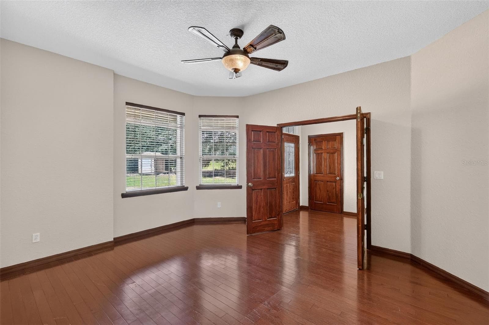 A dedicated formal living room or home office features elegant double doors, hardwood floors, and peaceful views of the property. - 4617 ROUND LAKE RD, APOPKA