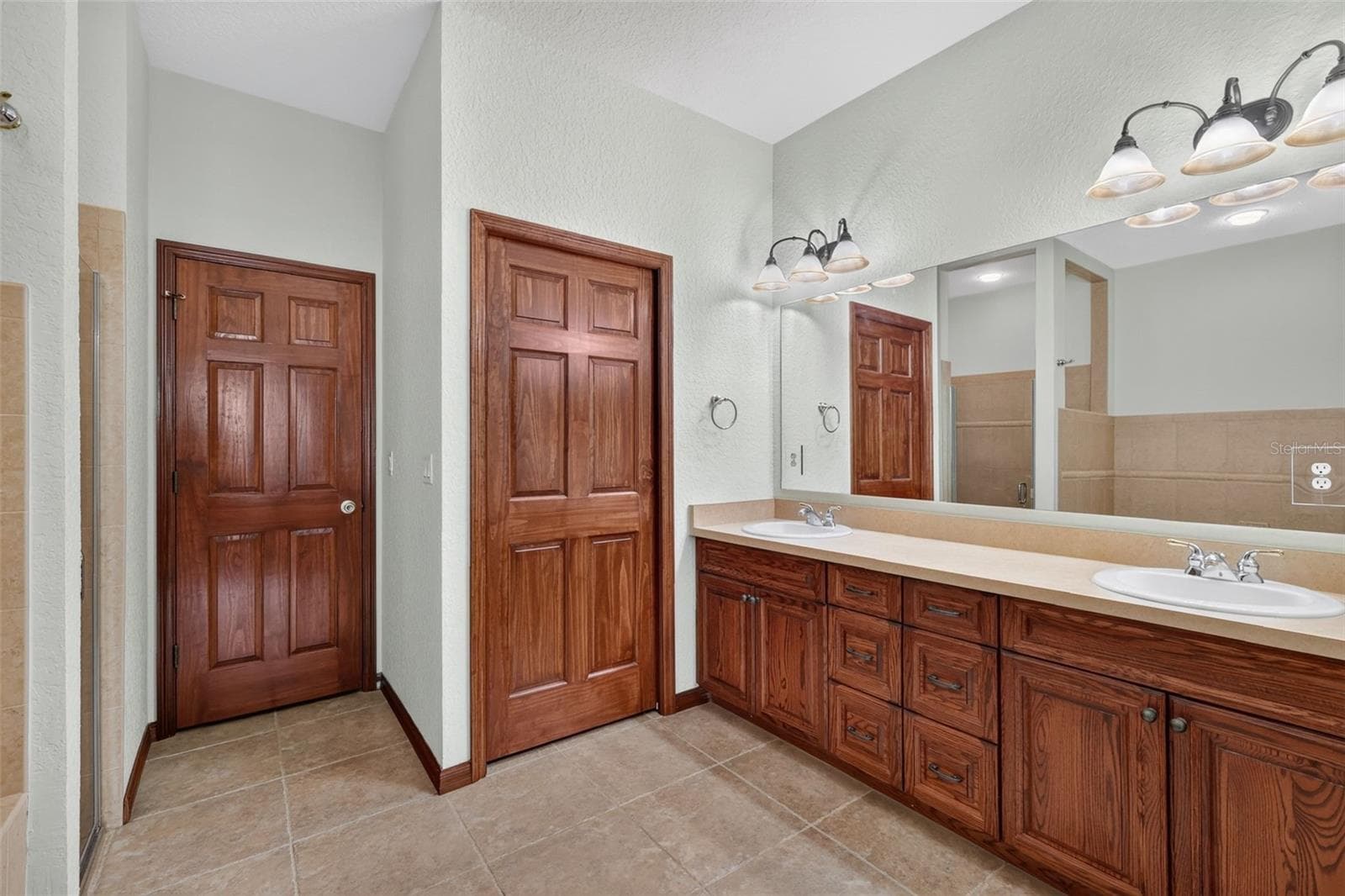 The en-suite bath features a long double vanity with rich oak cabinetry, plus separate walk-in shower and dedicated closet access. - 4617 ROUND LAKE RD, APOPKA