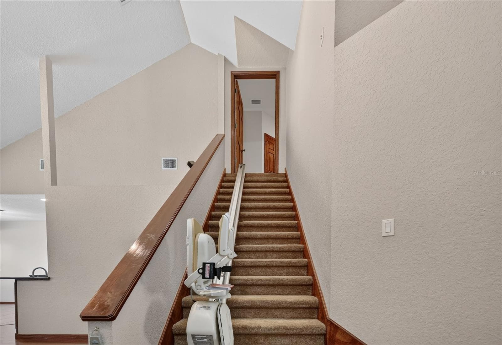 A wide staircase with a convenient stair lift connects the two levels, ensuring easy access for everyone in the household. - 4617 ROUND LAKE RD, APOPKA