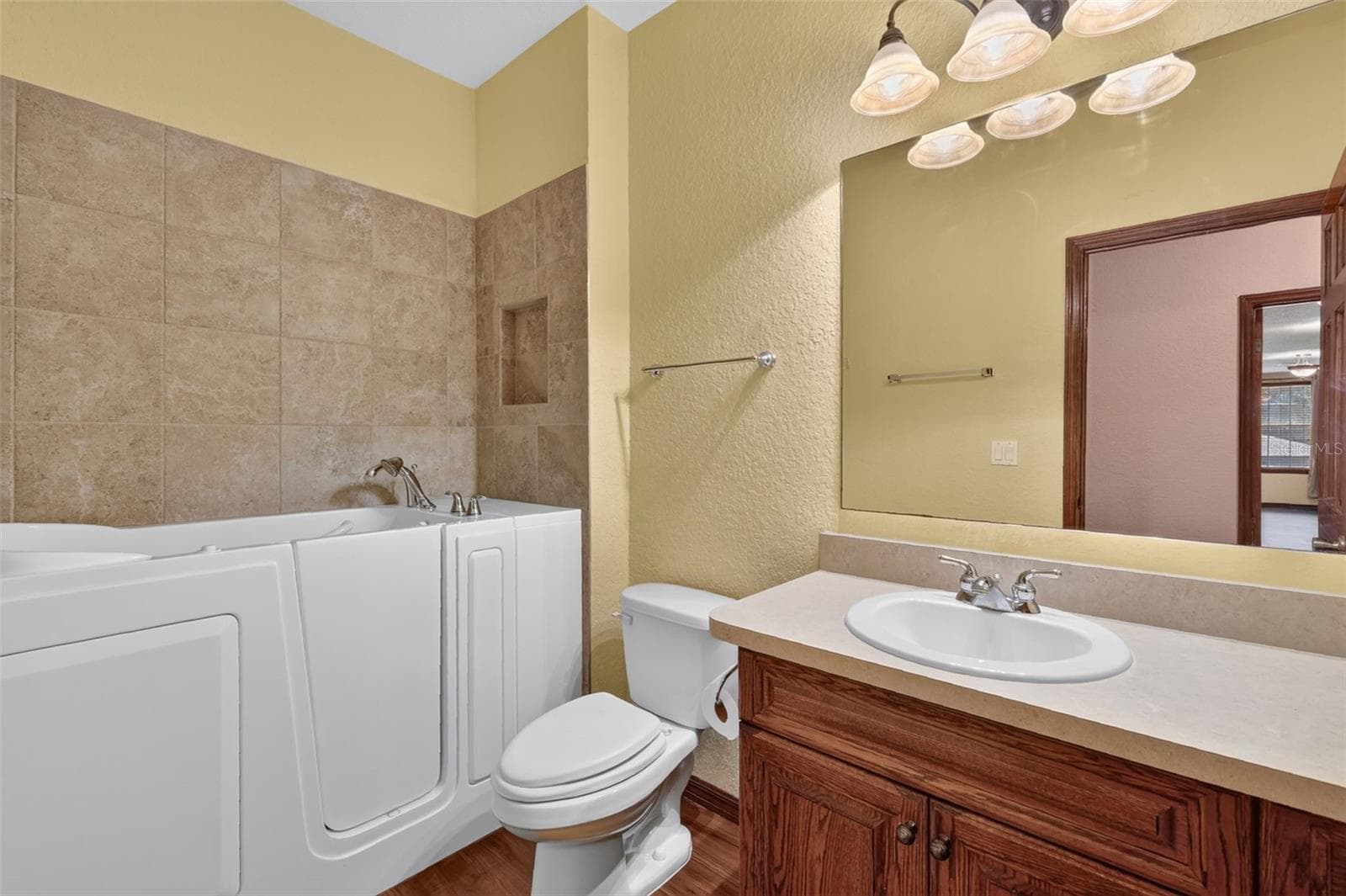A full bathroom upstairs features a walk-in tub with tile surround and a built-in niche for added convenience. - 4617 ROUND LAKE RD, APOPKA