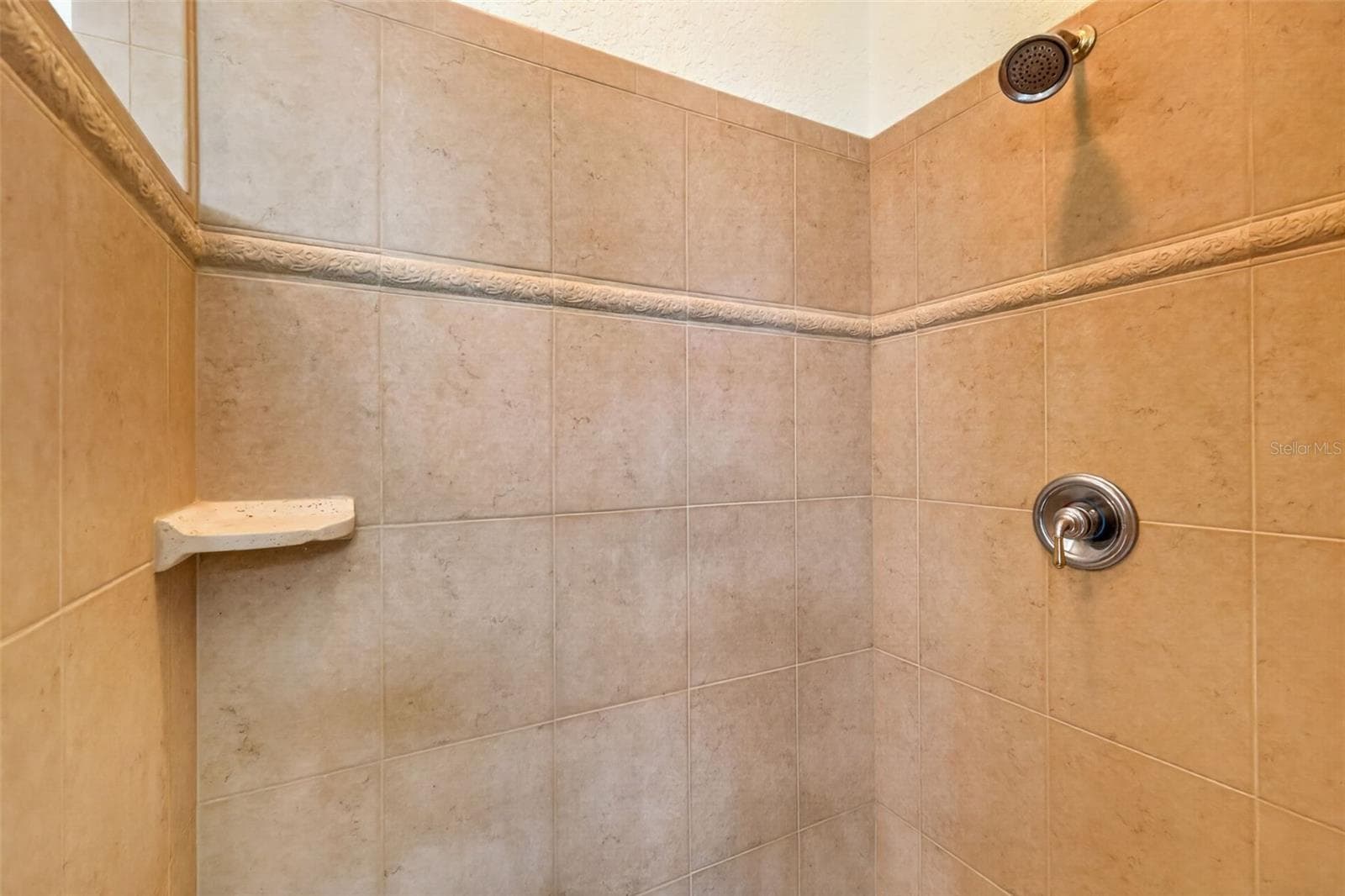 Quality tile work with decorative accents and a built-in corner shelf elevate the primary shower experience - 4617 ROUND LAKE RD, APOPKA
