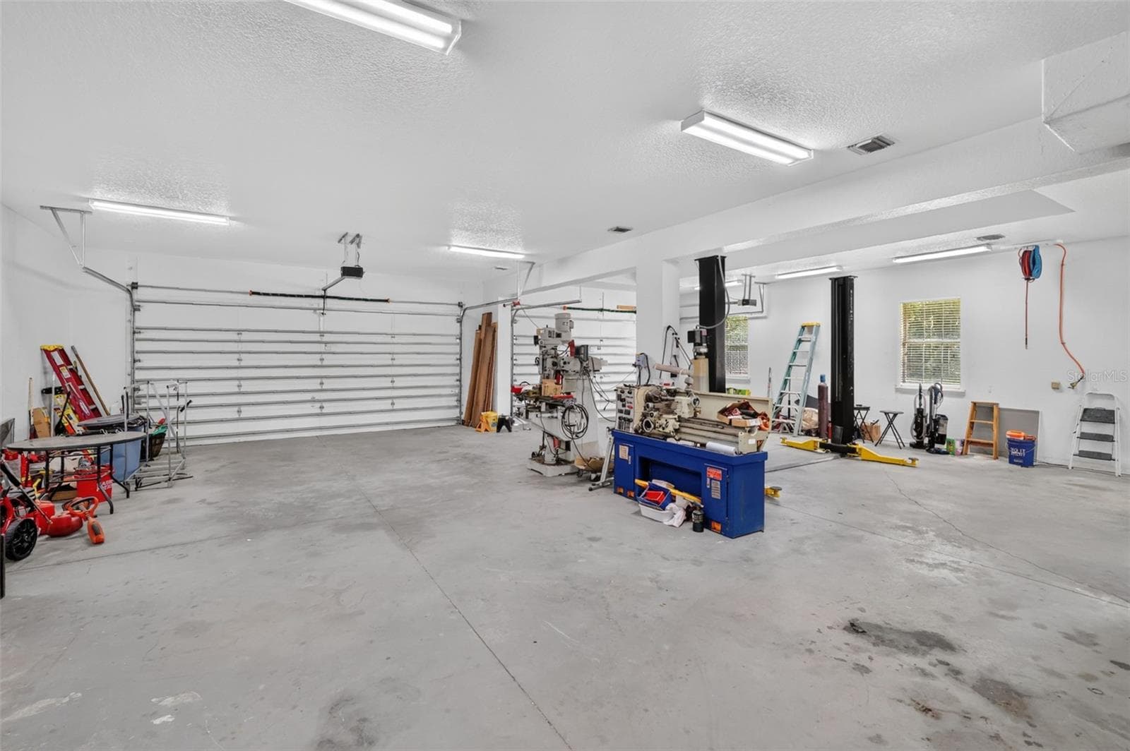 Dual two-car garage doors provide easy drive-through access, while the retractable air reel and built-in lift are ready for any job. - 4617 ROUND LAKE RD, APOPKA
