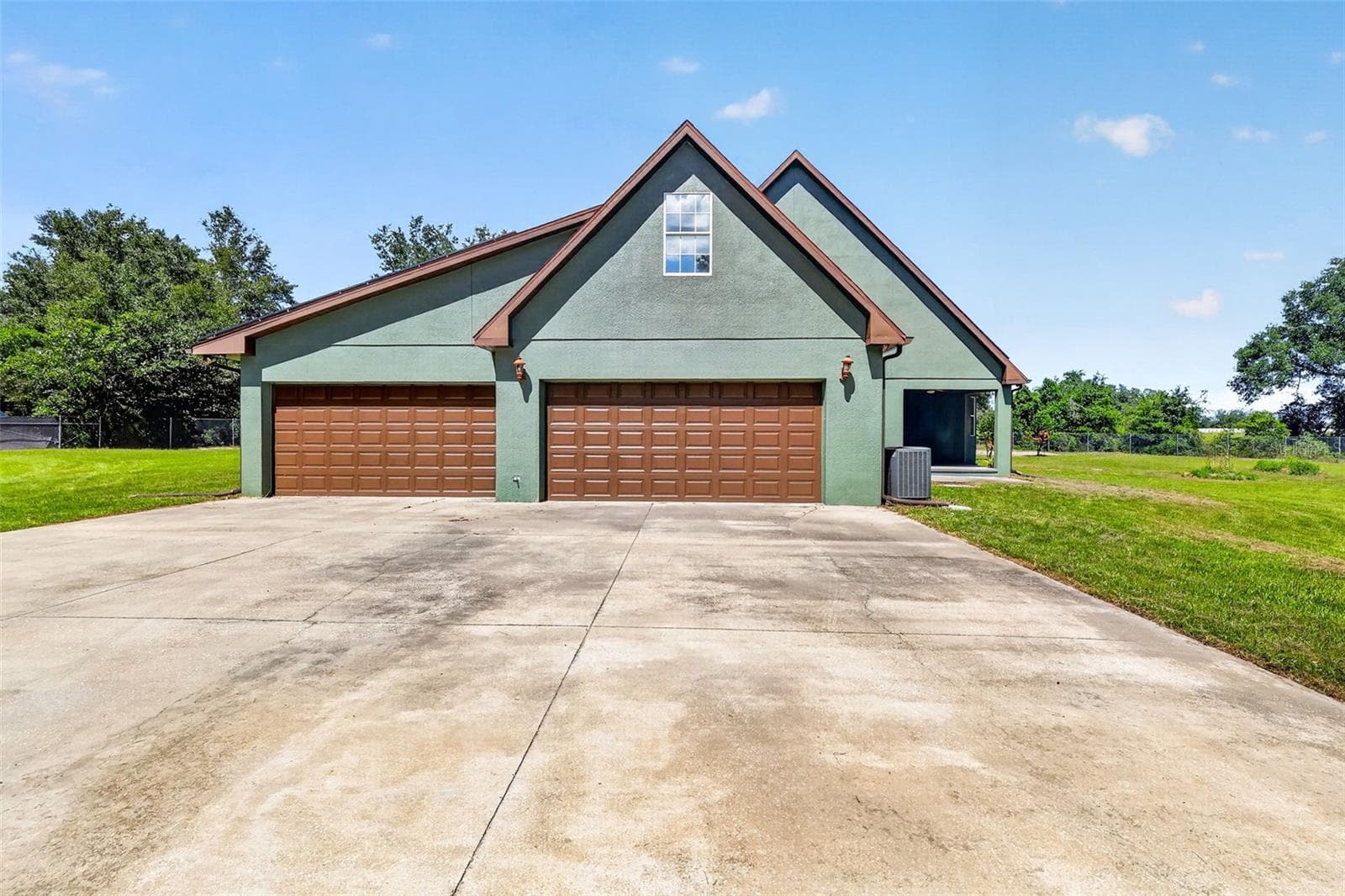 The 4+ car workshop matches the home's architectural style with a wide concrete drive, coach lanterns, and its own dedicated AC system. - 4617 ROUND LAKE RD, APOPKA