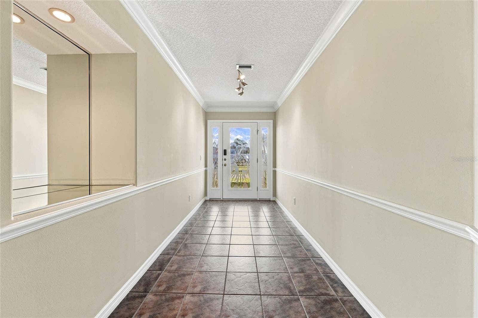 Entry hallway — Tiled entry hallway with crown molding, chair rail, and a glass-paneled front door with sidelights. - 342 N 12TH ST, FLAGLER BEACH