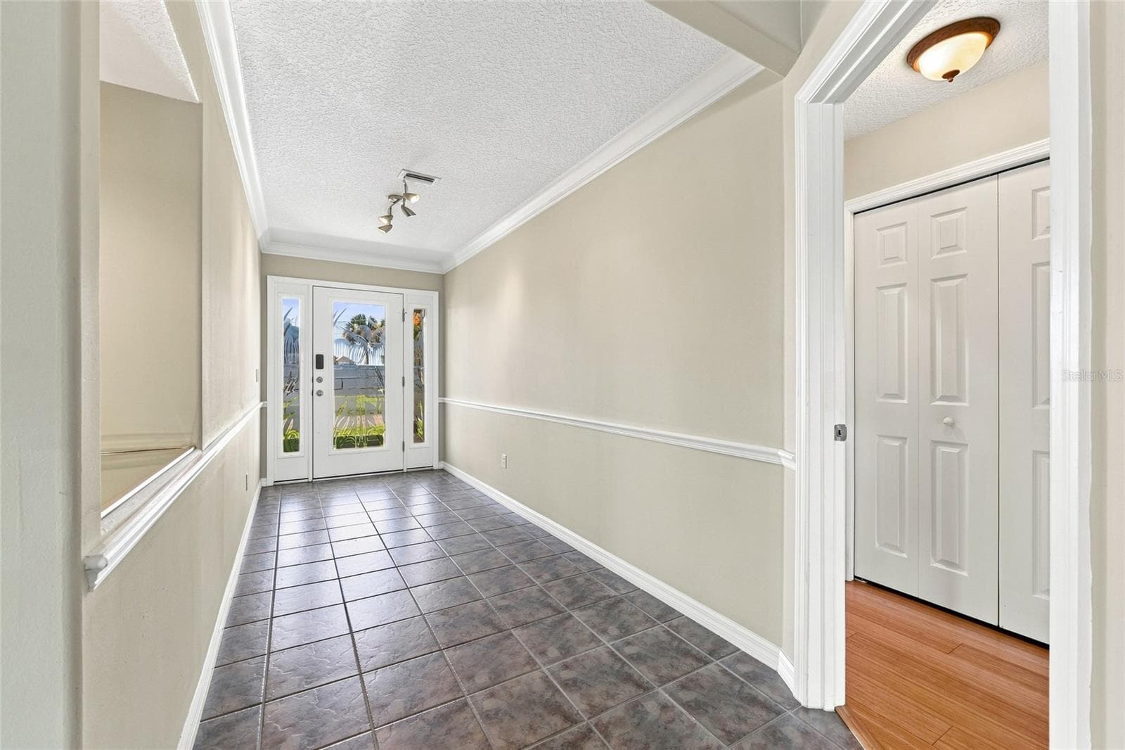 Entry foyer — Foyer with tile flooring, crown molding, and double closet doors, opening into the main living area. - 342 N 12TH ST, FLAGLER BEACH