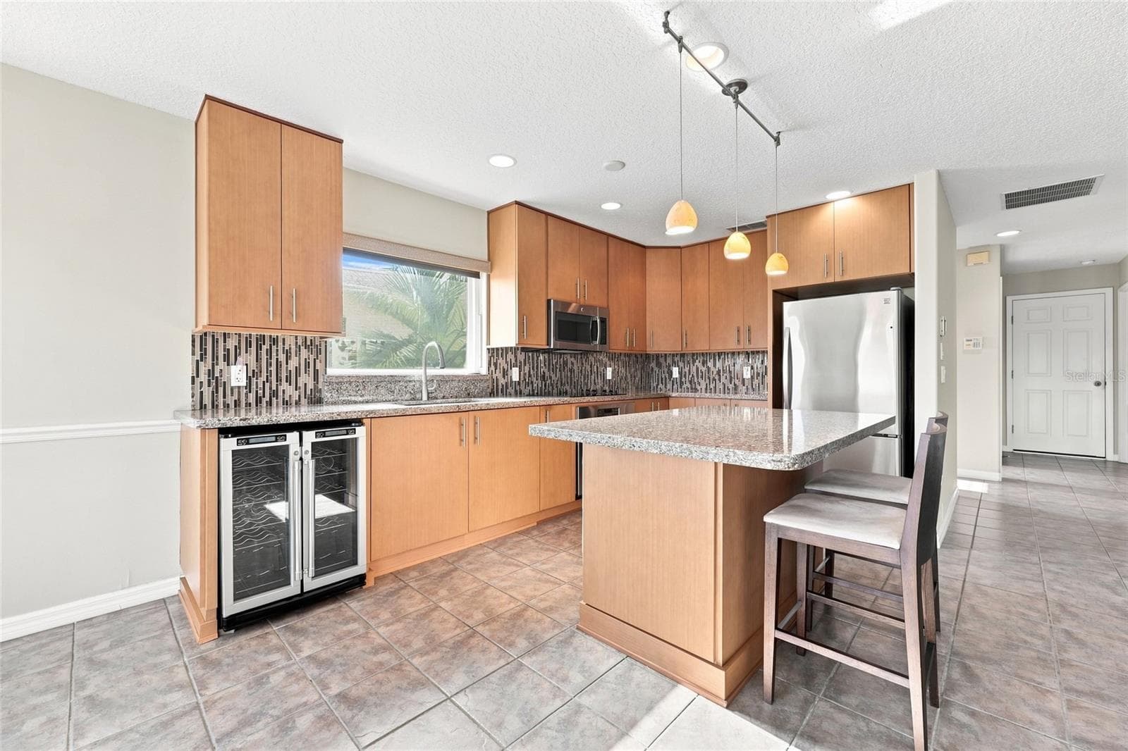 Kitchen — Kitchen with dual built-in wine and beverage refrigerators, granite countertops, and stainless appliances. - 342 N 12TH ST, FLAGLER BEACH