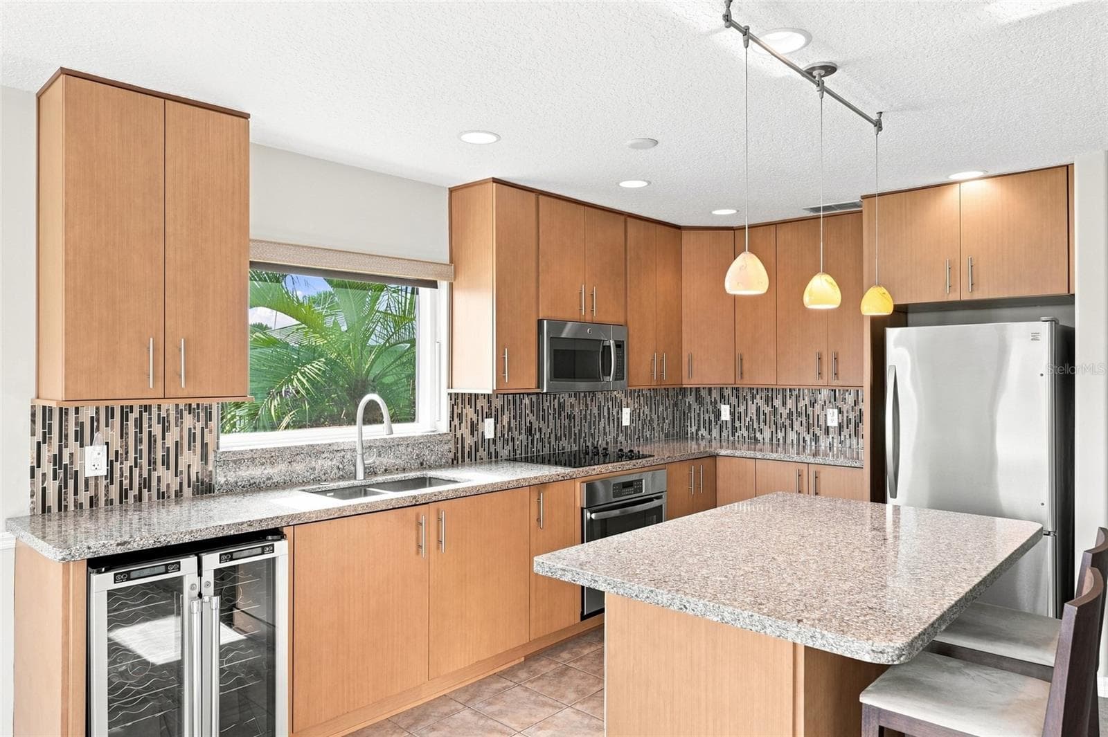 Kitchen entry — Kitchen opening to a French door leading to a screened porch, with chandelier, granite island, and staircase visible in the background. - 342 N 12TH ST, FLAGLER BEACH
