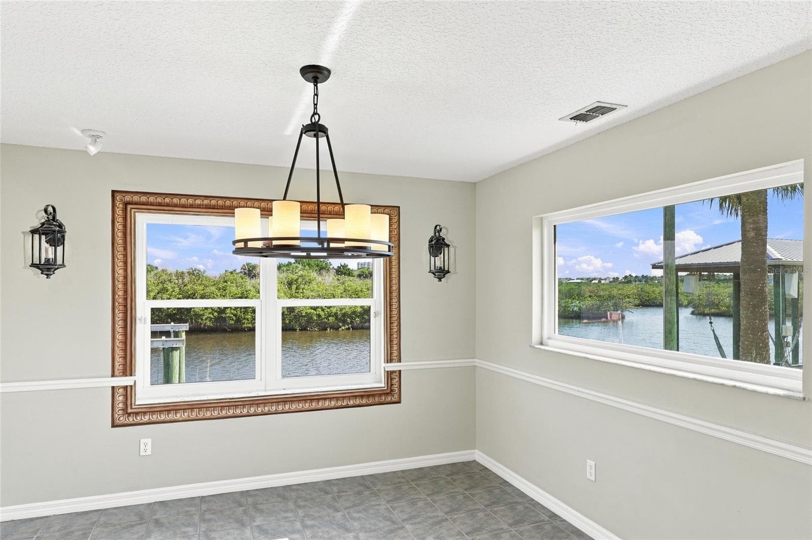reakfast nook — Breakfast nook with picture-frame window overlooking the canal and a second window framing a palm tree and neighboring dock. - 342 N 12TH ST, FLAGLER BEACH