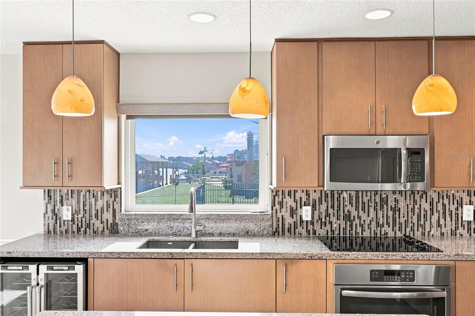 Kitchen — Close view of glass mosaic tile backsplash, granite countertops, and dual beverage refrigerators. - 342 N 12TH ST, FLAGLER BEACH