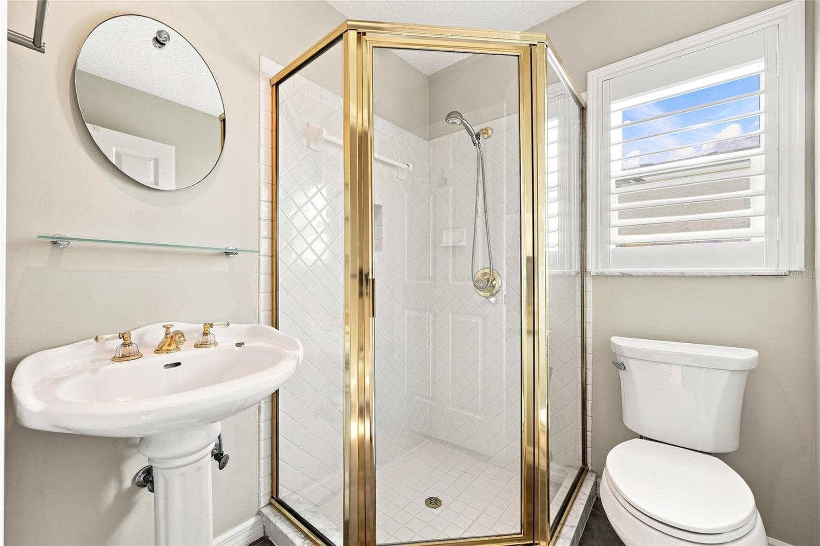 Bathroom — Bathroom with pedestal sink, brass fixtures, and a corner glass-enclosed shower with brass frame and diamond-pattern tile. - 342 N 12TH ST, FLAGLER BEACH