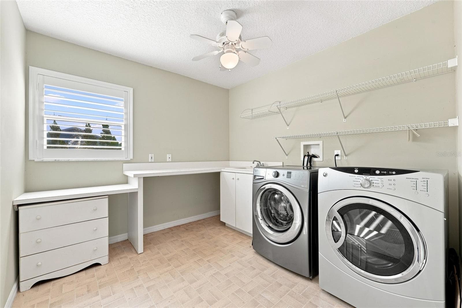 Laundry room — Laundry room with side-by-side washer and dryer, wire shelving, and a built-in folding counter. - 342 N 12TH ST, FLAGLER BEACH