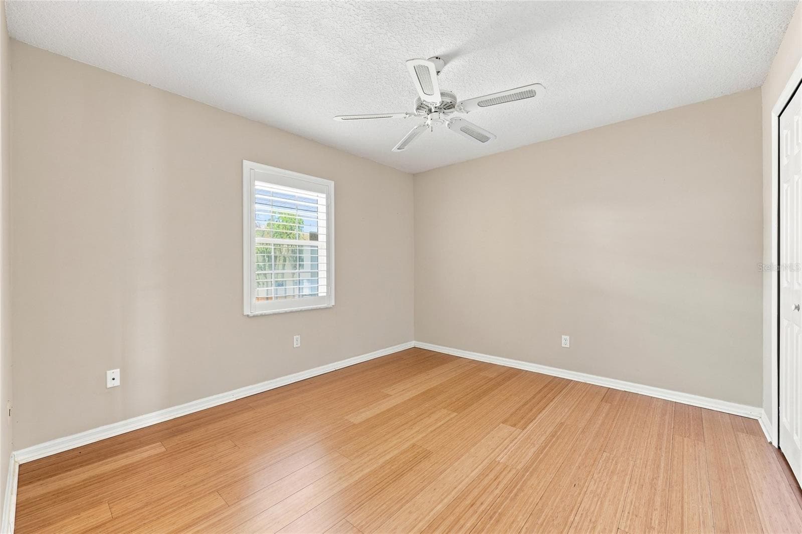 Bedroom 2 — Bedroom with wood flooring, ceiling fan, and a window with plantation shutters. - 342 N 12TH ST, FLAGLER BEACH