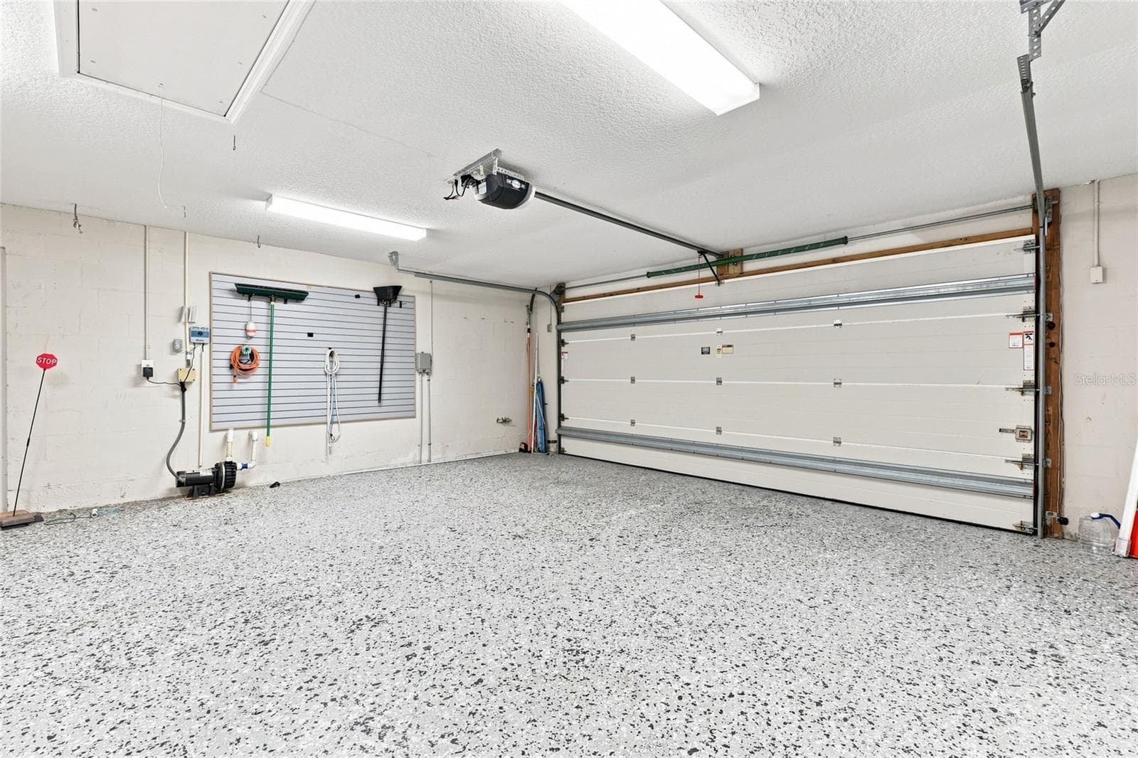 Garage — Two-car garage with epoxy-flake flooring, overhead storage access, and wall-mounted tool storage. - 342 N 12TH ST, FLAGLER BEACH