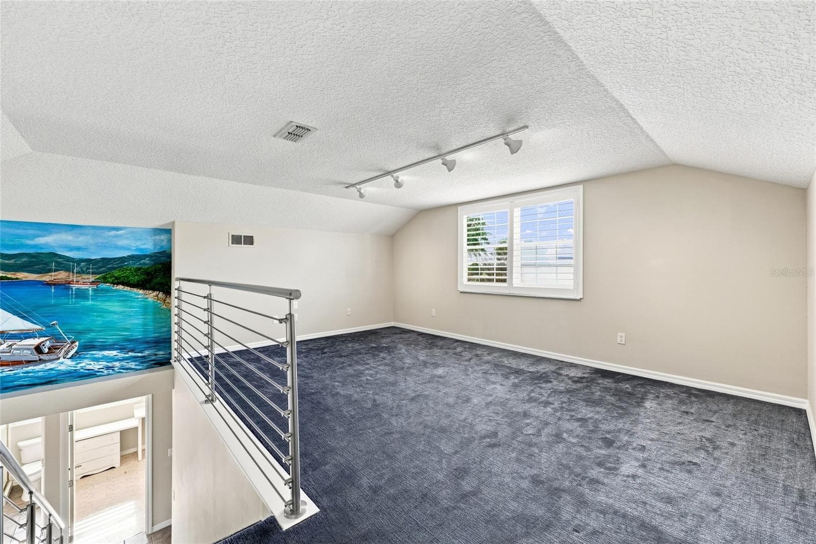 Loft — Loft area with plush carpet, cable railing overlooking the great room, and a large window with plantation shutters. - 342 N 12TH ST, FLAGLER BEACH