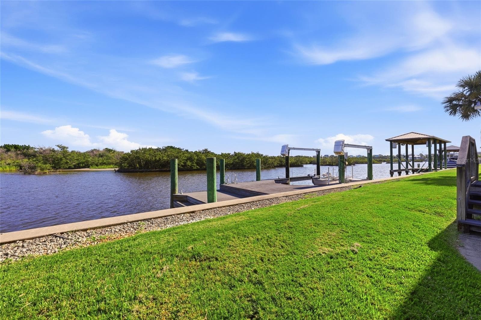 Dock and boat lift — Composite dock with two boat lift areas, one holding a jet ski, positioned on the canal with direct sightline down the waterway toward the mangroves. - 342 N 12TH ST, FLAGLER BEACH