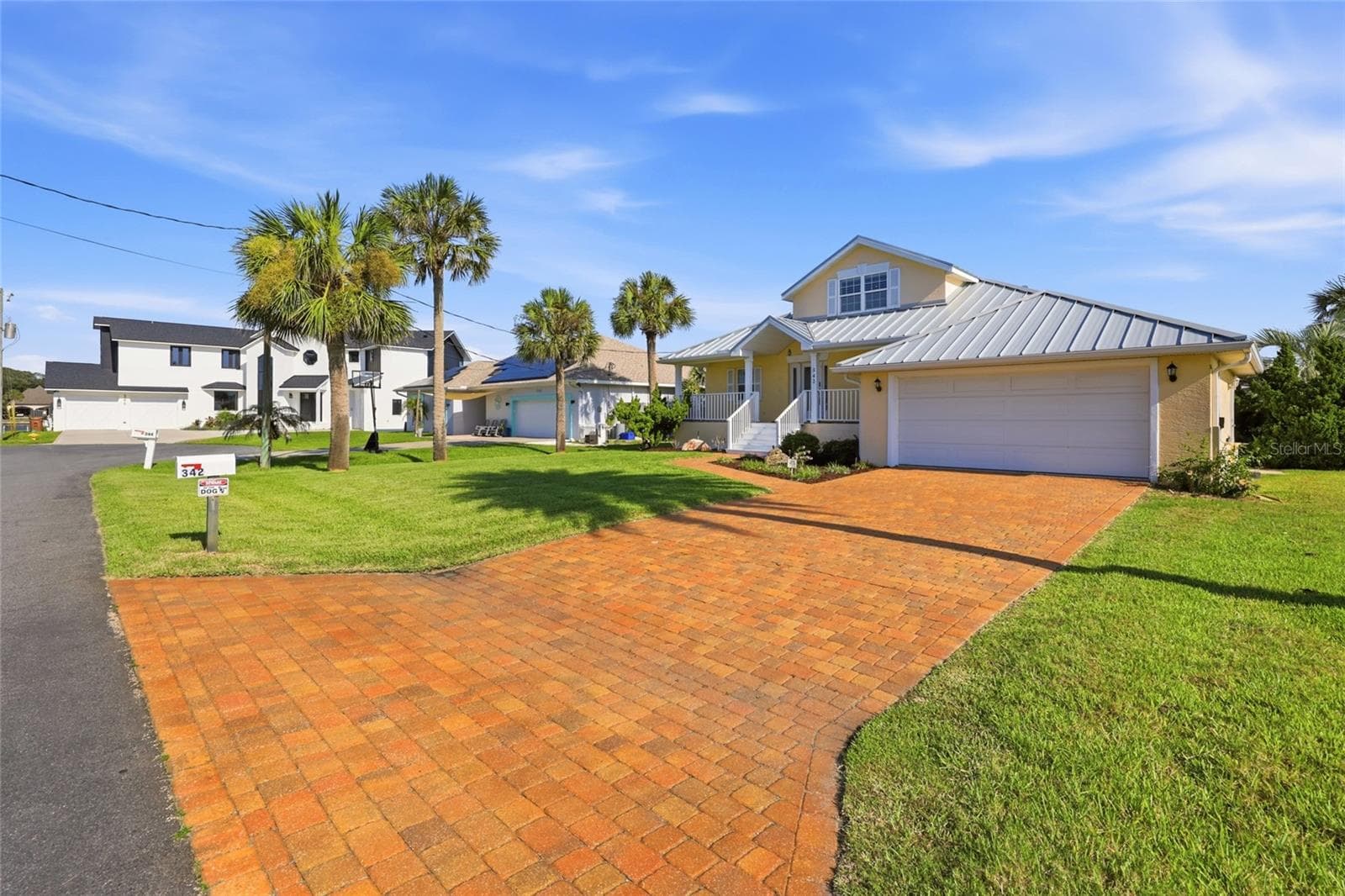 Front exterior — Front elevation with standing-seam metal roof, second-story dormer window, covered entry porch, paver driveway, and 2-car garage. - 342 N 12TH ST, FLAGLER BEACH