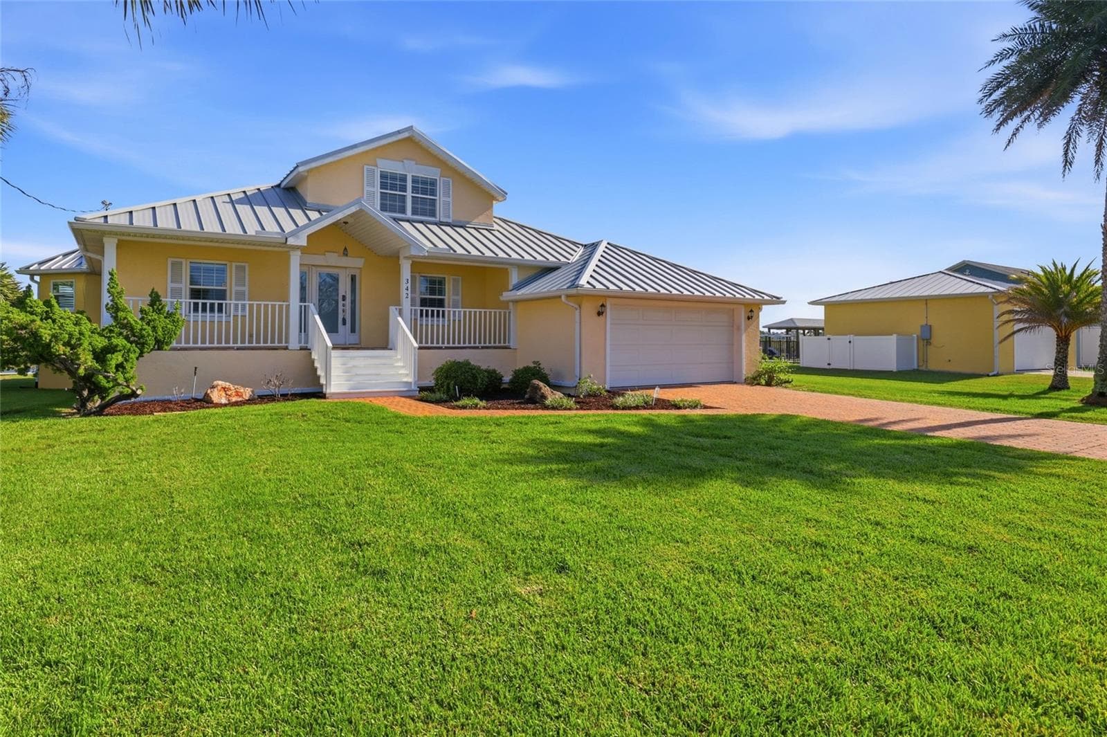 Front exterior — Close front elevation with house numbers on the entry column, wraparound porch with white railings, and covered entry with French doors. - 342 N 12TH ST, FLAGLER BEACH