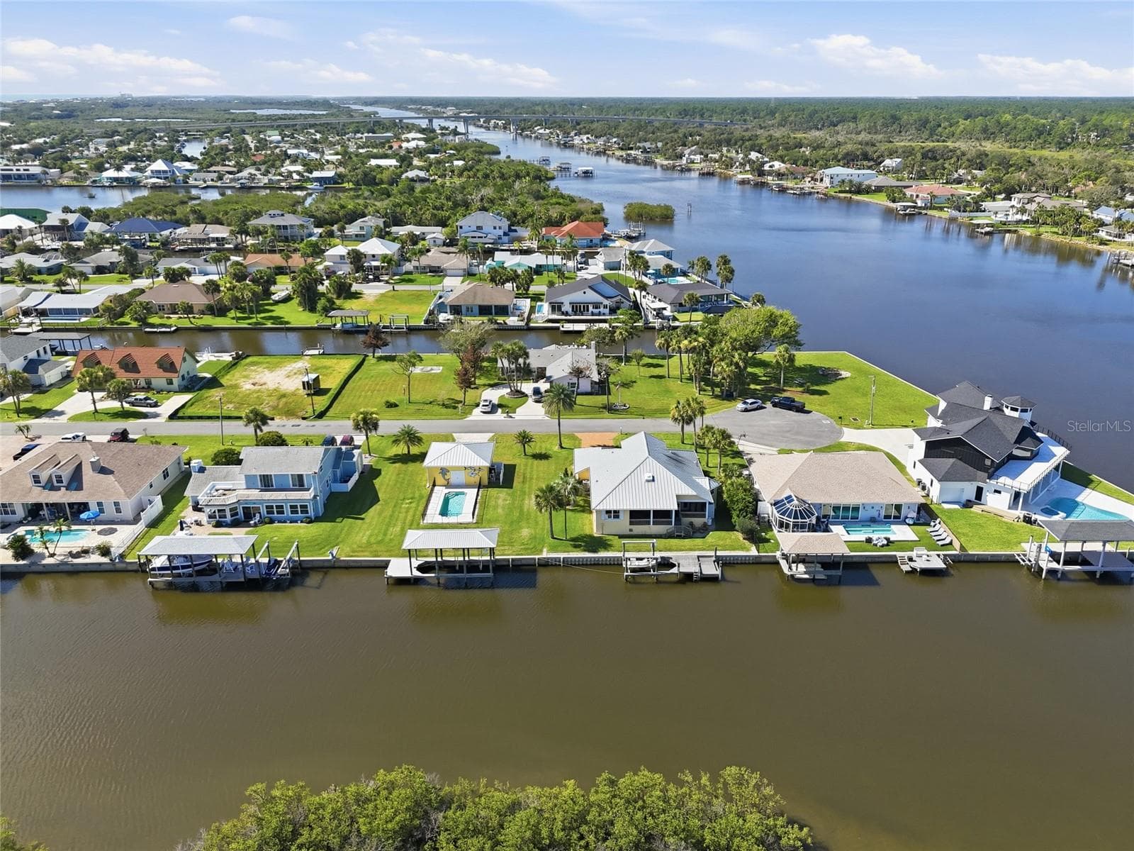 Aerial view — Wide aerial view down the canal toward the Intracoastal Waterway, mangrove islands, and the Atlantic Ocean, with the property's canal frontage and dock visible in the foreground. - 342 N 12TH ST, FLAGLER BEACH