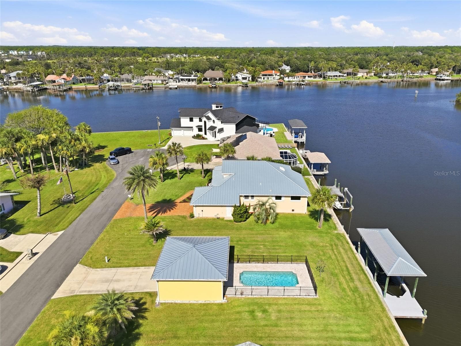 Aerial view — Aerial view of the canal-front neighborhood looking toward the Intracoastal Waterway, with the property's pool, detached structure, and dock visible among neighboring homes and private docks. - 342 N 12TH ST, FLAGLER BEACH