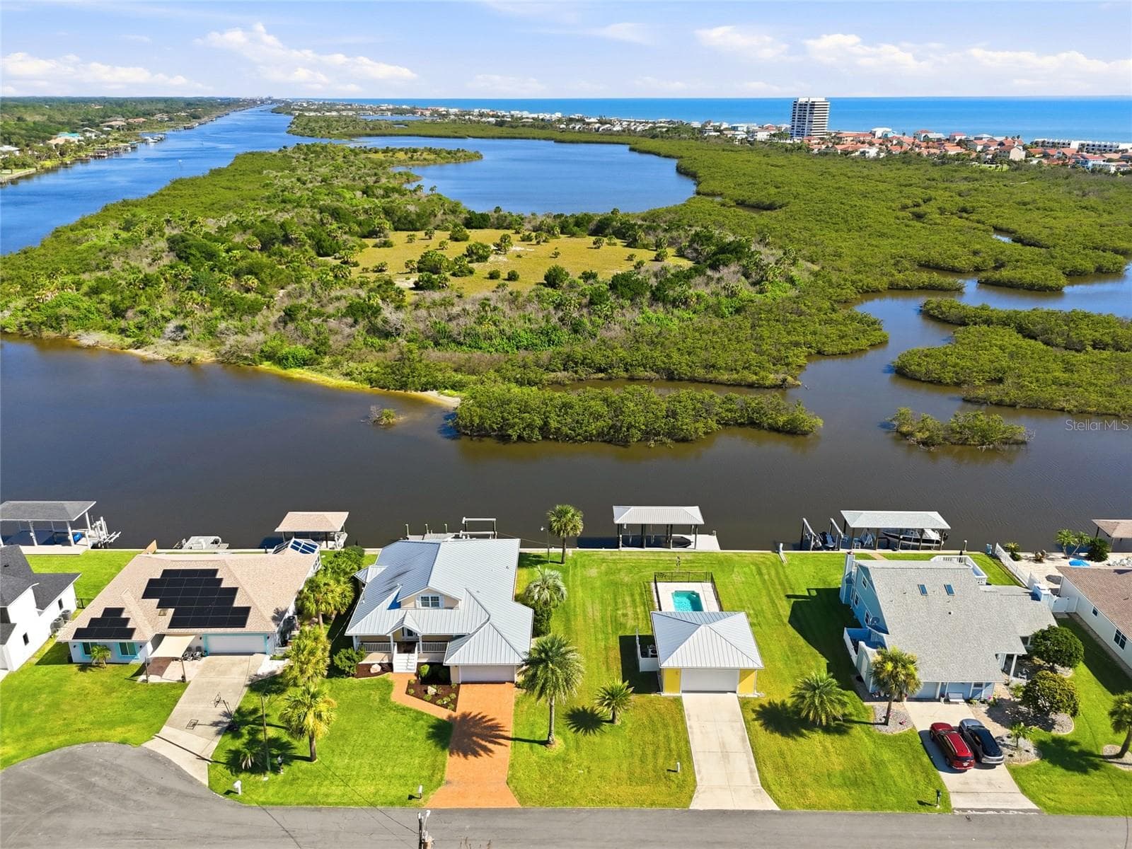 Aerial view — Aerial view of the property's dock, pool, and detached garage alongside neighboring canal-front homes with private docks. - 342 N 12TH ST, FLAGLER BEACH