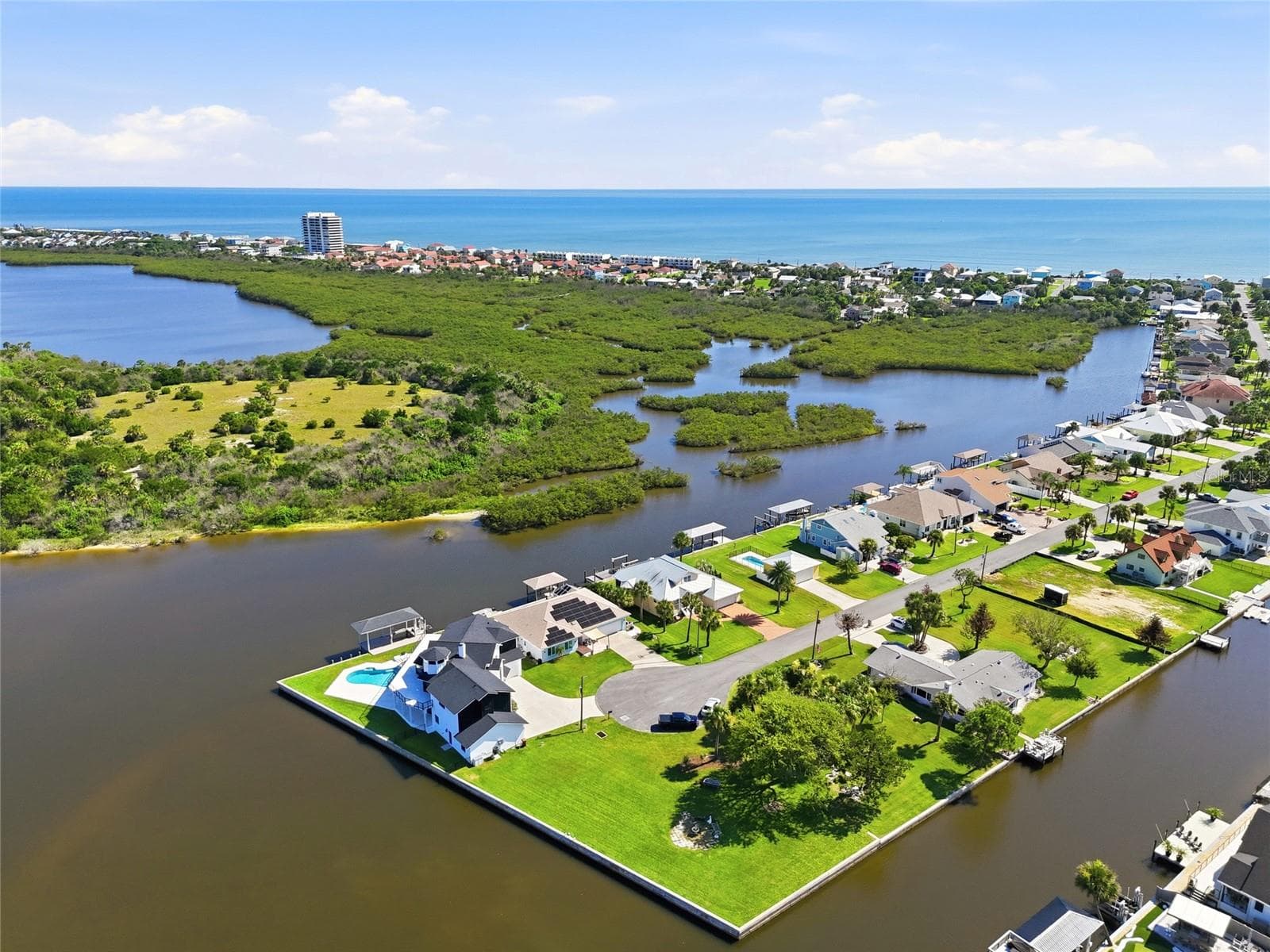 Aerial view — Aerial view of the canal-front neighborhood with the property visible among the mangrove islands and open water leading to the coast. - 342 N 12TH ST, FLAGLER BEACH