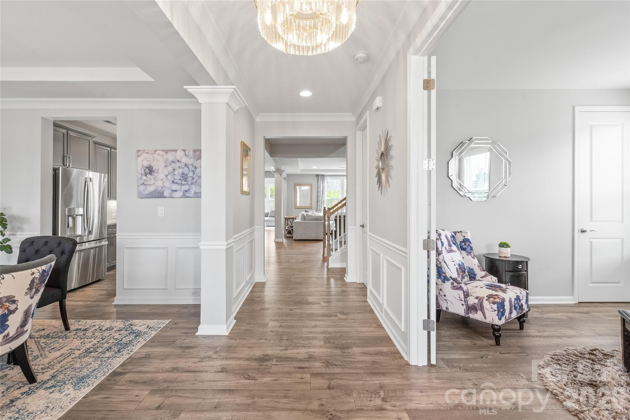 Step into a light-filled entry featuring cohesive LVP flooring, elegant custom trimwork, and updated designer lighting that immediately sets a sophisticated, modern tone. - 6440 Ancient Way, Fort Mill