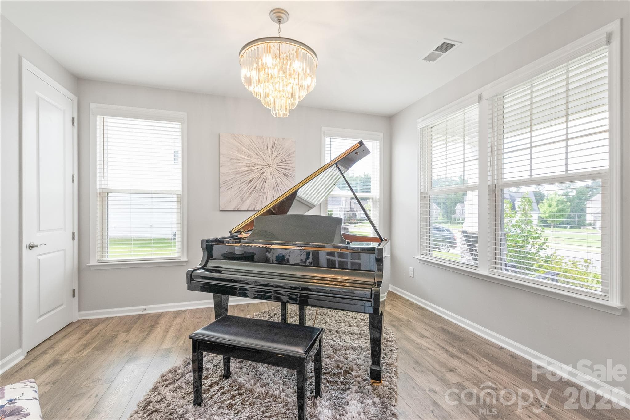 Located right off the entry, this versatile office or flex space is bathed in natural light, featuring rich LVP floors and a statement designer chandelier. - 6440 Ancient Way, Fort Mill