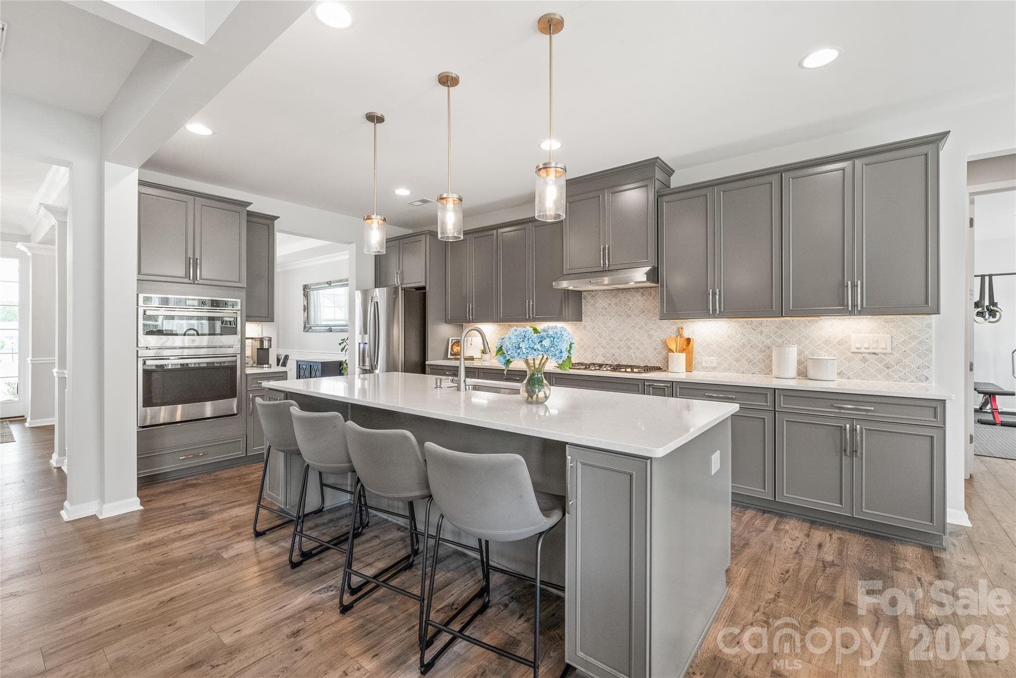 At the heart of the home, this gourmet chef’s kitchen shines with an oversized center island, soft-close cabinetry, sleek quartz countertops, stainless steel appliances, and a spacious walk-in pantry. - 6440 Ancient Way, Fort Mill