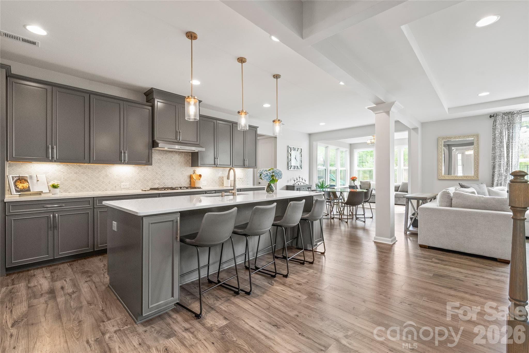 Illuminated by ambient under-cabinet lighting, crisp recessed lights, and beautiful statement pendants over the island, this kitchen glows with effortless warmth and style. - 6440 Ancient Way, Fort Mill