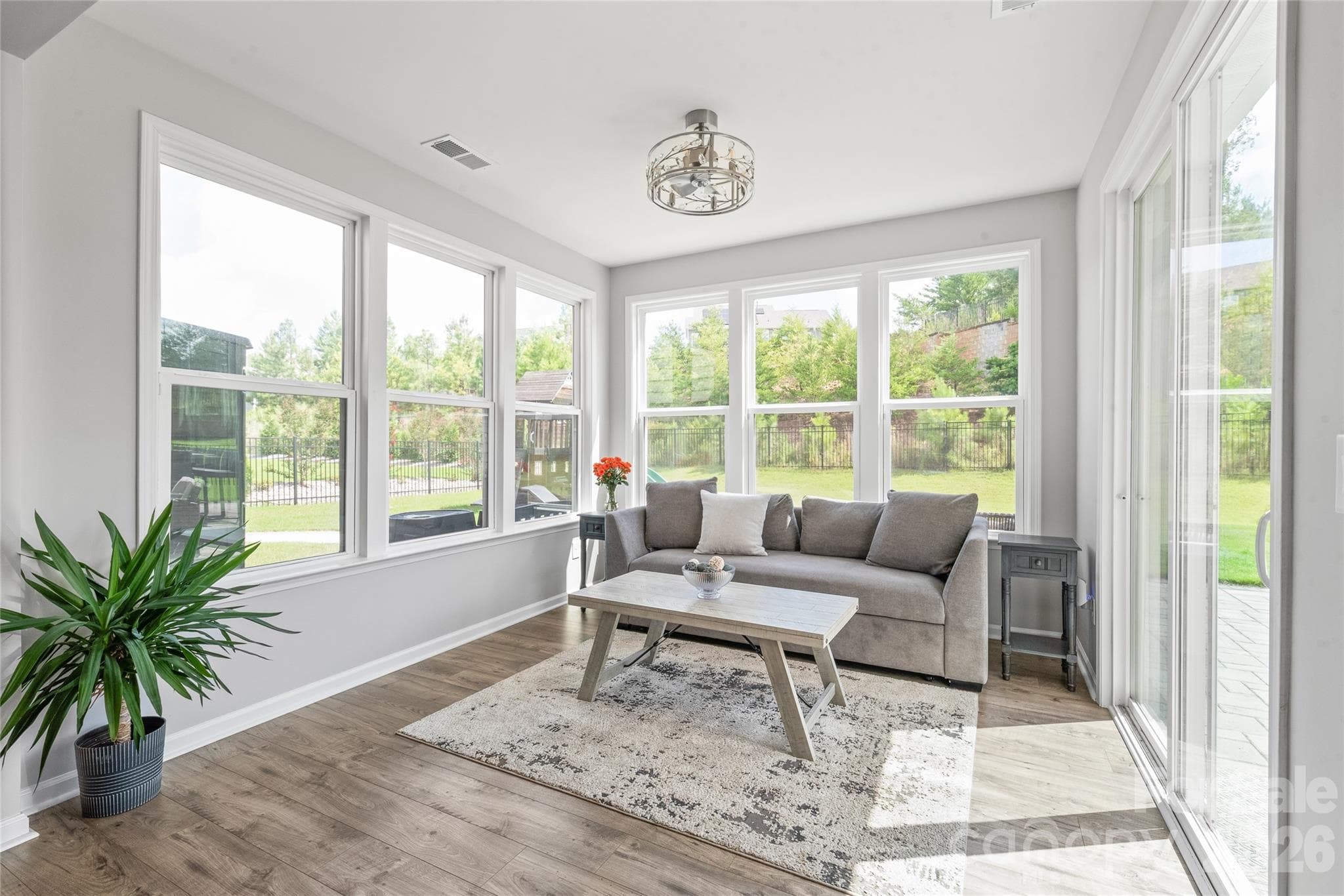 Framed by walls of windows and a sliding glass door, the light-filled sunroom effortlessly blends indoor comfort with seamless access to the outdoor living space. - 6440 Ancient Way, Fort Mill
