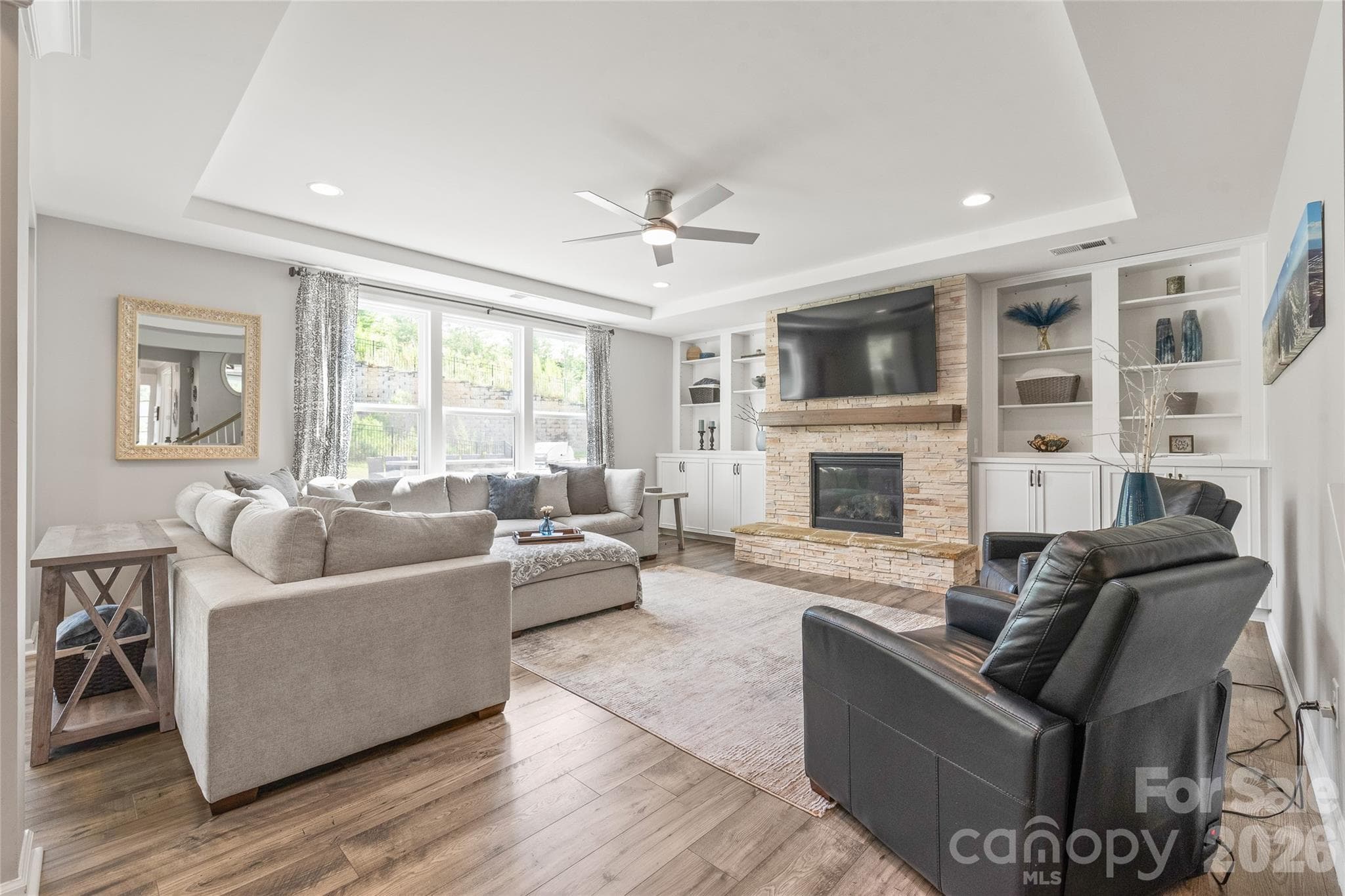 Anchored by a striking stone fireplace flanked by custom built-ins, the inviting living room offers a warm, spacious gathering spot bathed in natural light. - 6440 Ancient Way, Fort Mill