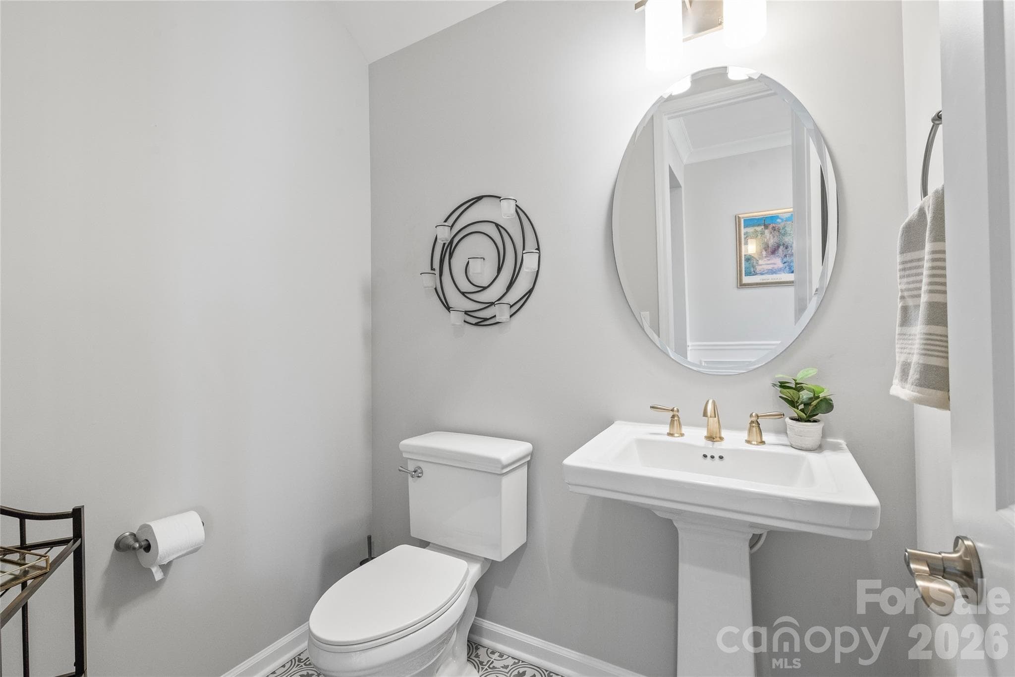 Tucked away for privacy, this main-level powder room features a classic pedestal sink ideal for guests. - 6440 Ancient Way, Fort Mill