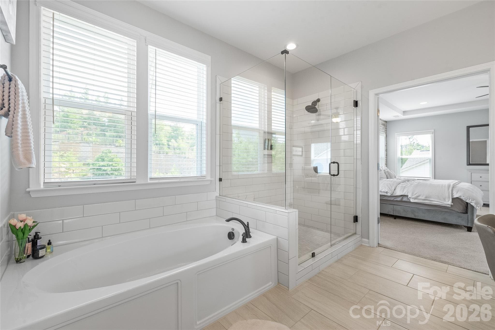 A spa-like retreat featuring a luxurious soaking tub and a spacious walk-in shower with a modern frameless glass surround. - 6440 Ancient Way, Fort Mill