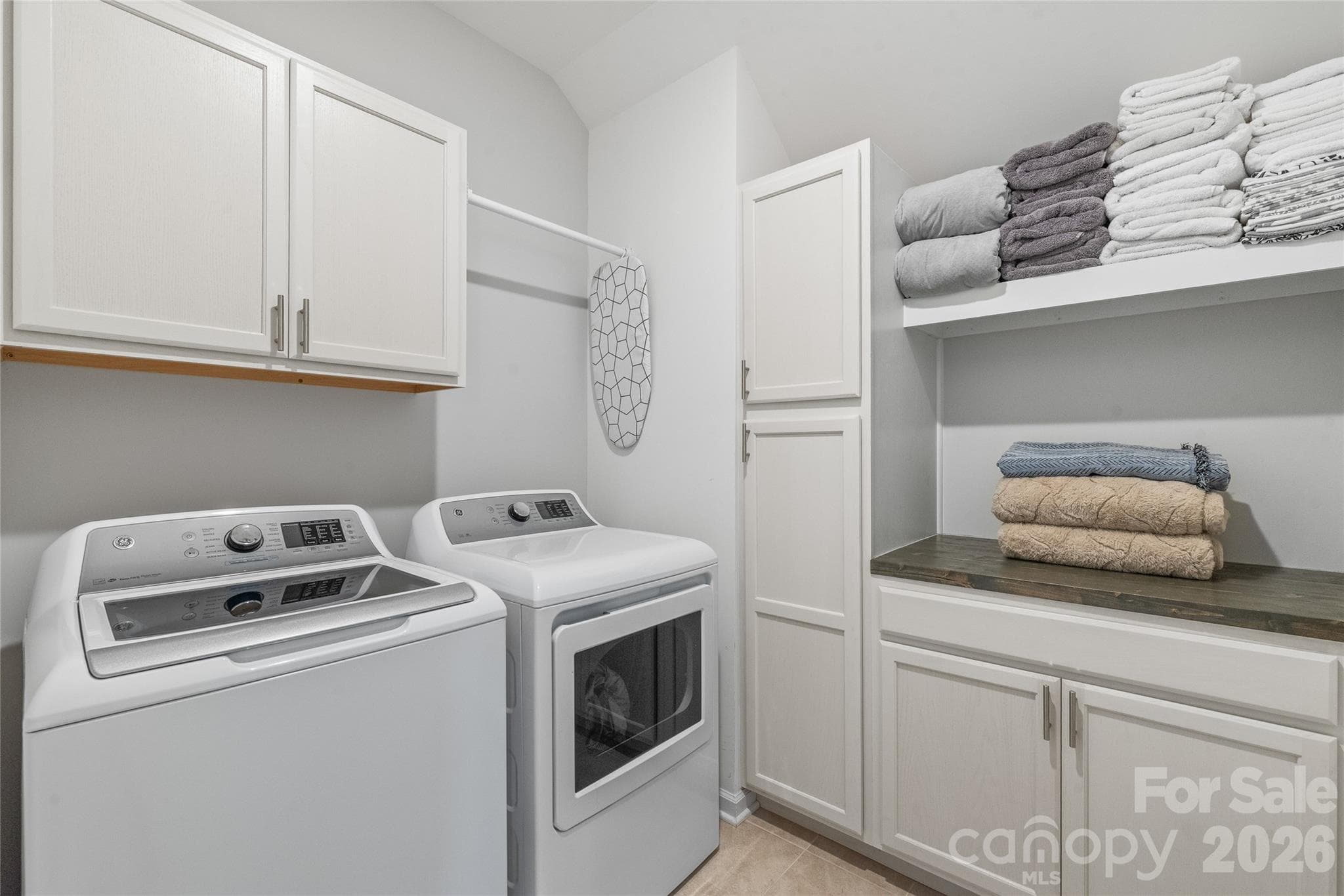 A dedicated laundry room equipped with custom built-in cabinets and continuous countertop space to make folding and sorting effortlessly organized. - 6440 Ancient Way, Fort Mill