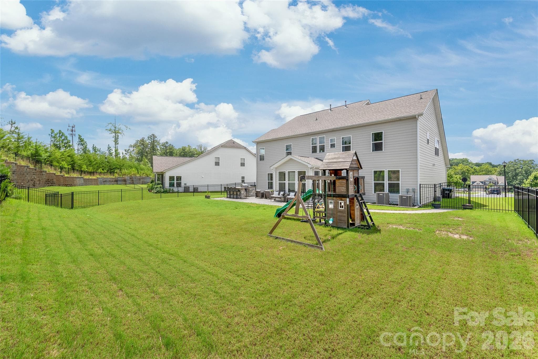 A fully fenced, level backyard that offers privacy and plenty of open space to run...complete with a built-in playset for endless outdoor fun. - 6440 Ancient Way, Fort Mill