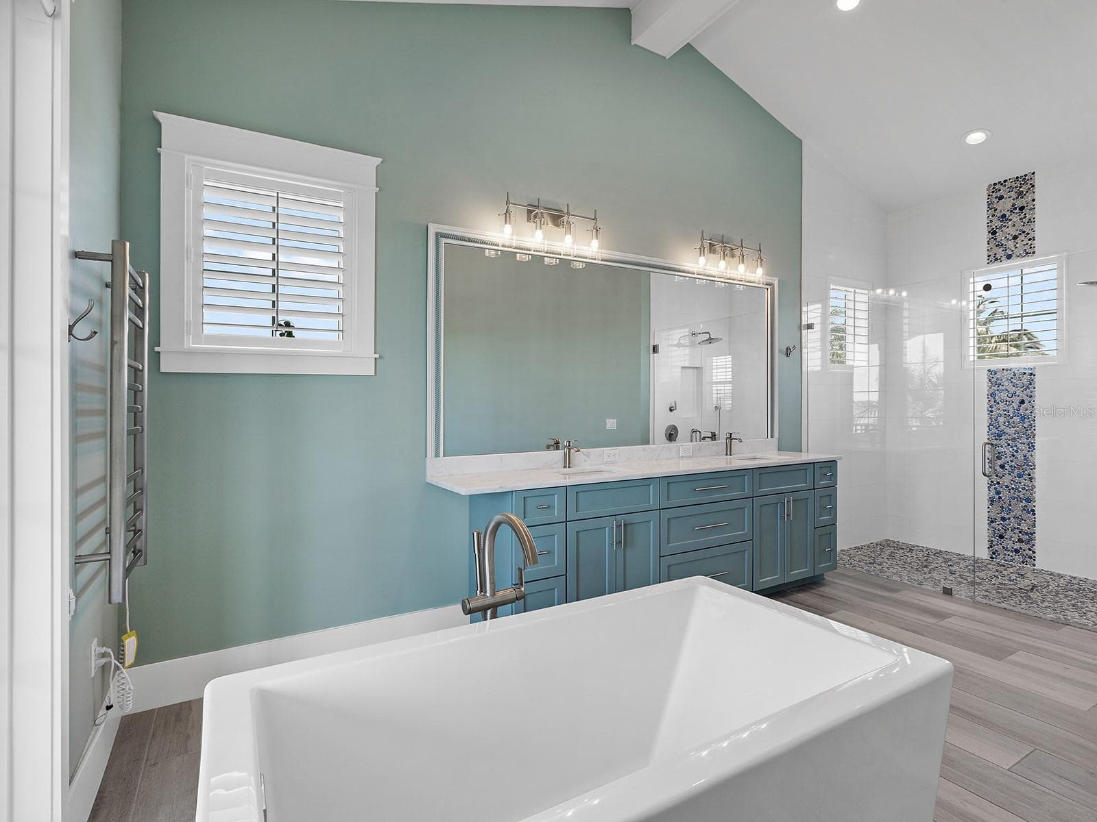 Spa-inspired primary ensuite featuring a freestanding soaking tub positioned to take in quiet river views, double vanity, and a walk-in pebble-tile shower - 4024 11TH STREET CT W, PALMETTO