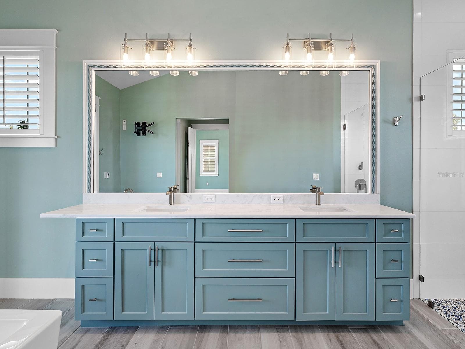 Spanning double vanity featuring elegant light teal cabinetry, a massive full-width mirror with dual vanities, and white quartz countertops - 4024 11TH STREET CT W, PALMETTO