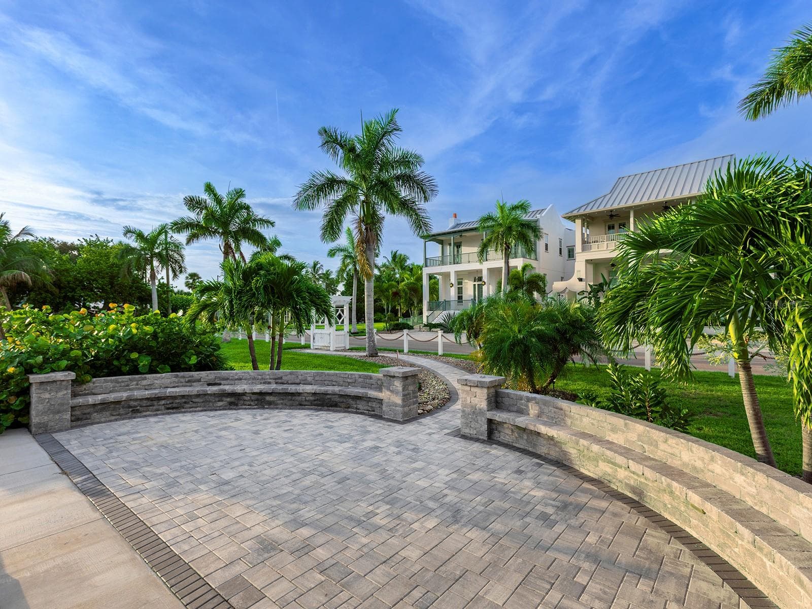 Serene waterfront patio space with custom paver stones and curved stone seating, nestled among lush tropical landscaping beside your dock - 4024 11TH STREET CT W, PALMETTO