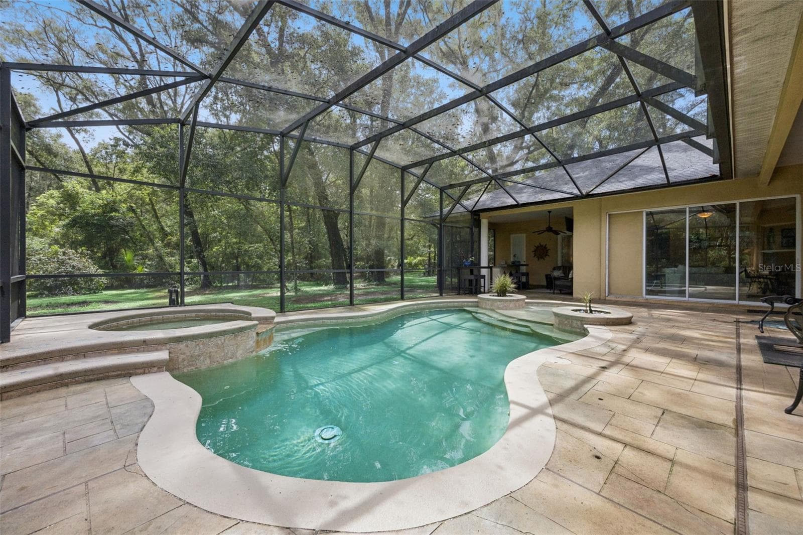Another view of the pool showcases the generous screened deck and wooded backdrop. - 30440 JUBILEE WAY, SORRENTO