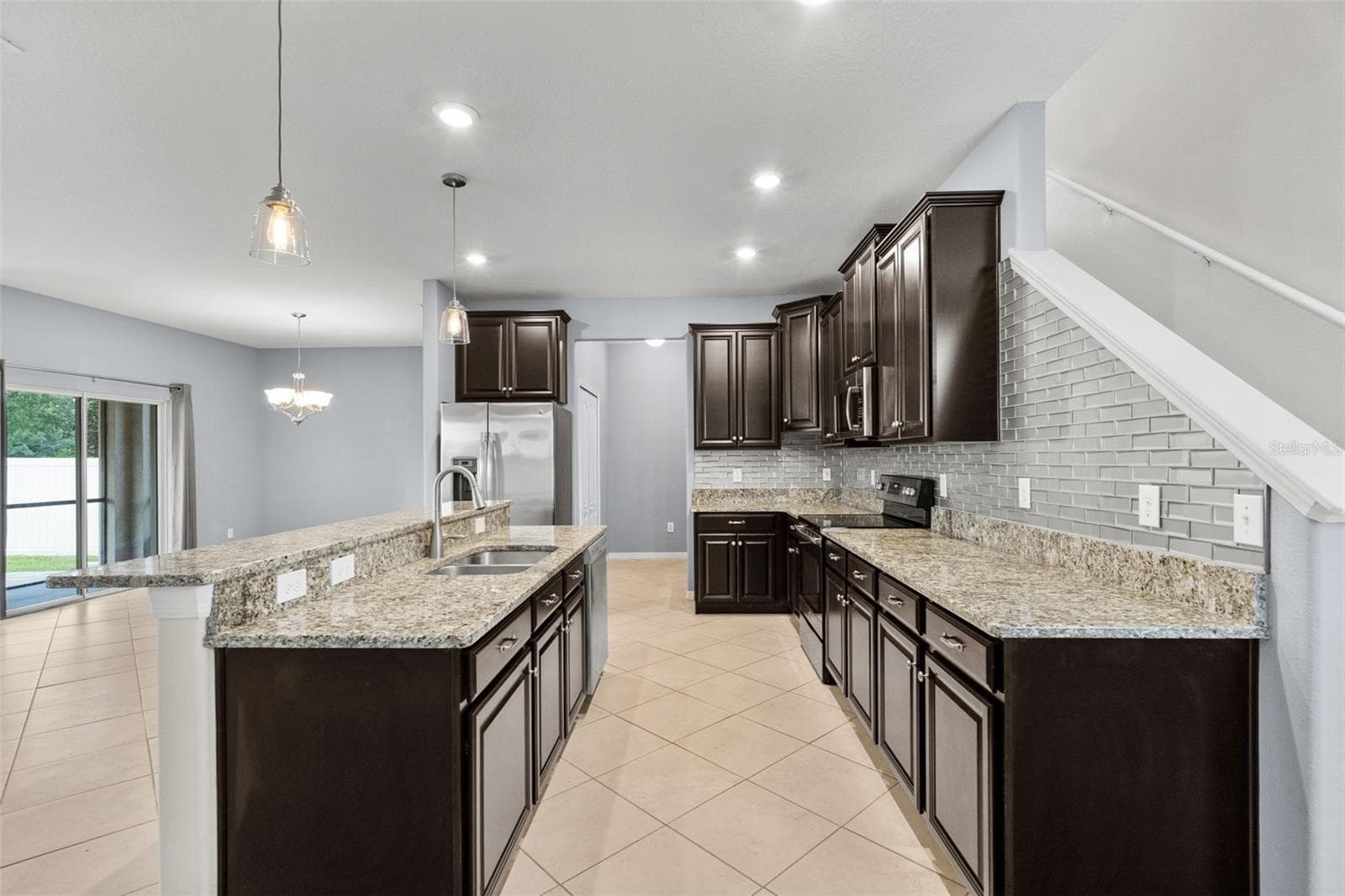 Kitchen — Well-appointed kitchen with granite countertops, stainless-steel appliances, abundant cabinetry, and decorative tile backsplash. - 13728 REINDEER CIR, HUDSON