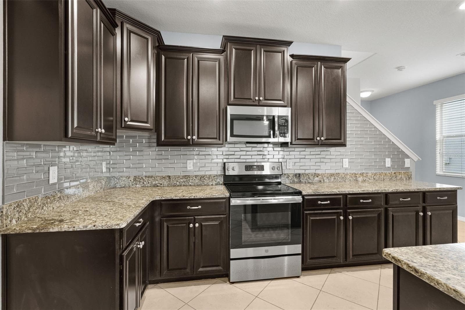 Kitchen — Granite countertops, stainless-steel appliances, rich cabinetry, and an extended backsplash complete this spacious kitchen. - 13728 REINDEER CIR, HUDSON