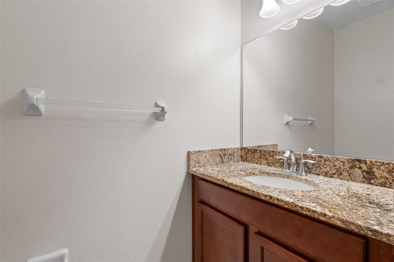 Half Bathroom — Convenient first-floor half bathroom featuring a granite-topped vanity and large mirror. - 13728 REINDEER CIR, HUDSON