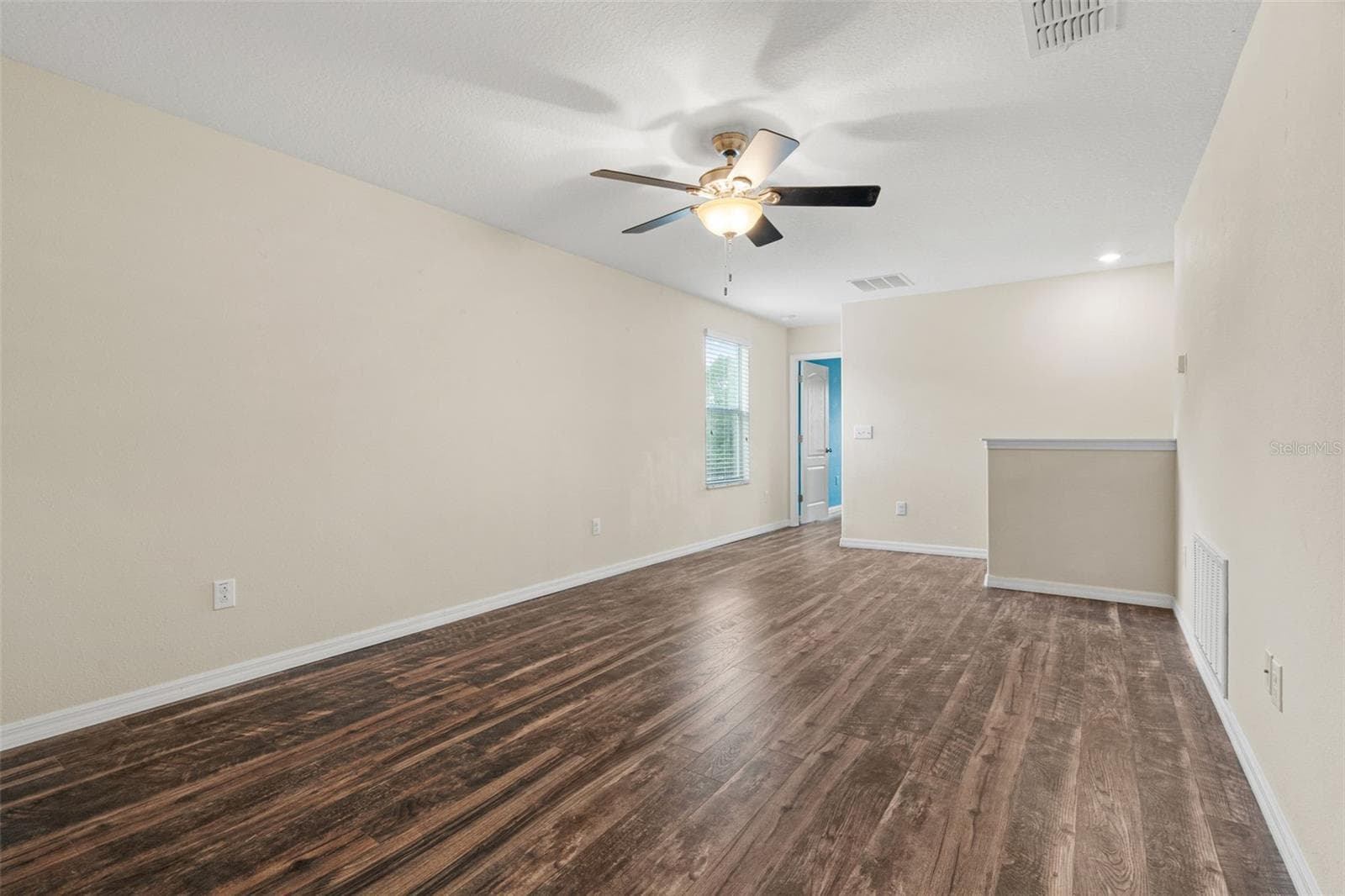 Upstairs Loft — Expansive second-floor loft with wood-look flooring and ceiling fan offers versatile additional living space. - 13728 REINDEER CIR, HUDSON