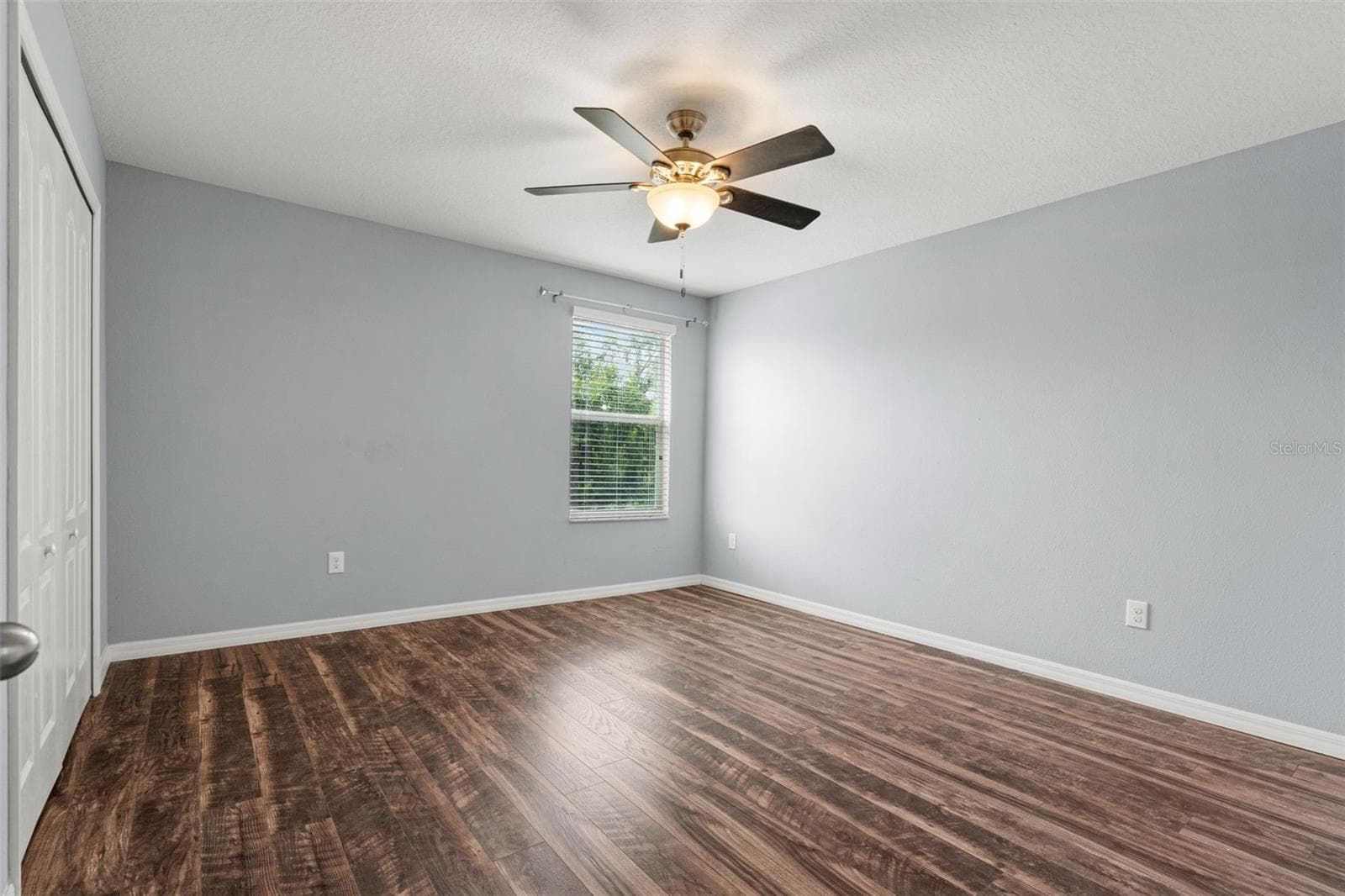 Bedroom – Bright bedroom with wood-look flooring, ceiling fan, window for natural light, and ample closet space. - 13728 REINDEER CIR, HUDSON