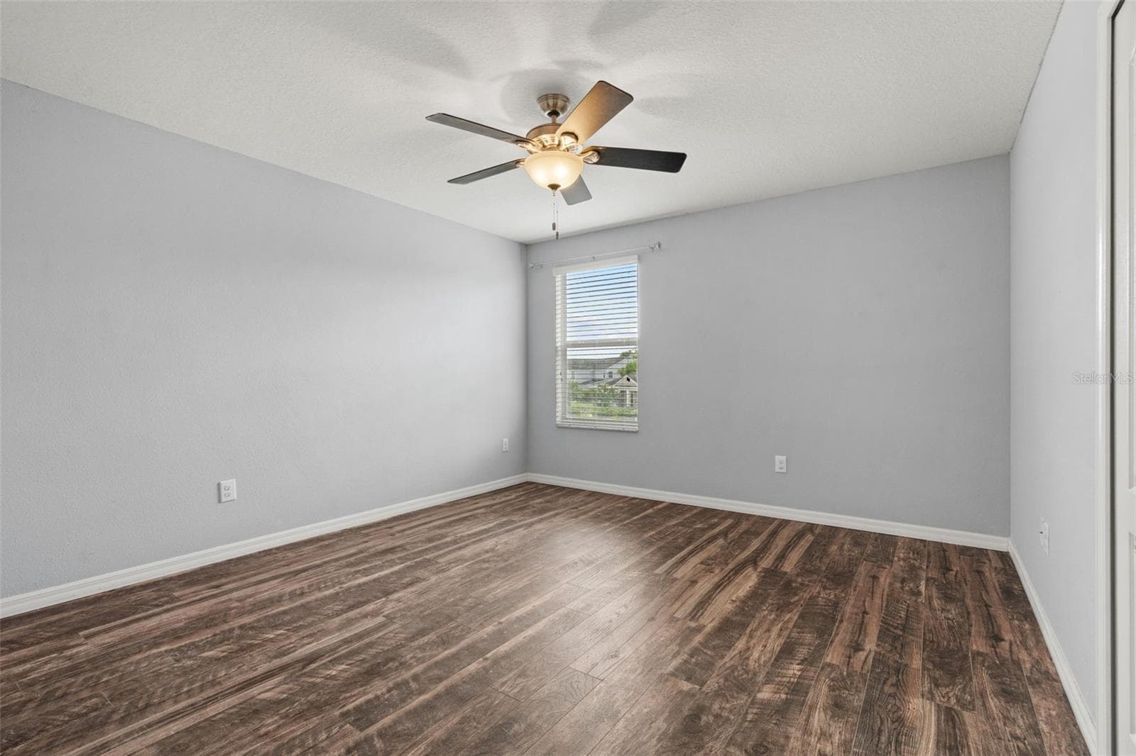 Bedroom – Alternate bedroom view highlighting the spacious layout, natural light, ceiling fan, and wood-look flooring. - 13728 REINDEER CIR, HUDSON