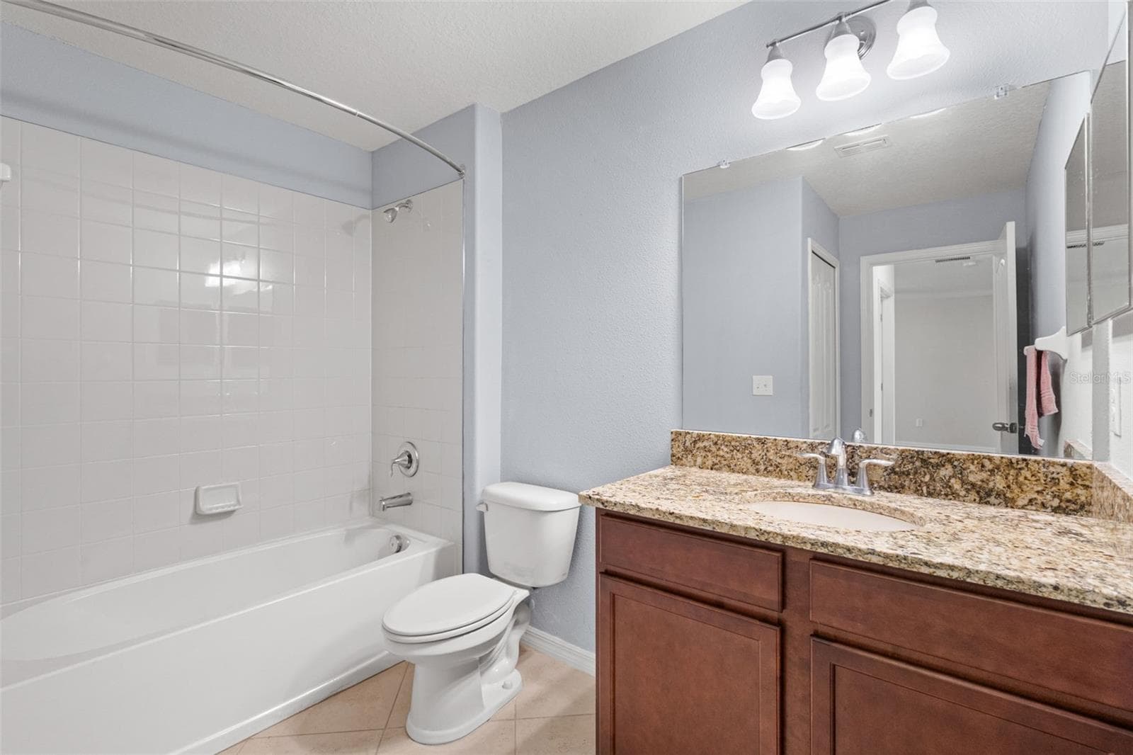 Full Bathroom – Full bathroom featuring a tub/shower combination, granite countertop vanity, large mirror, and tile flooring. - 13728 REINDEER CIR, HUDSON